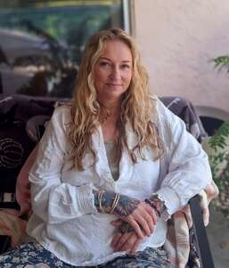 Margo Dandreano photo of margo sitting in chair with white shirt.